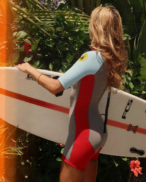 Woman in wetsuit holding surf board